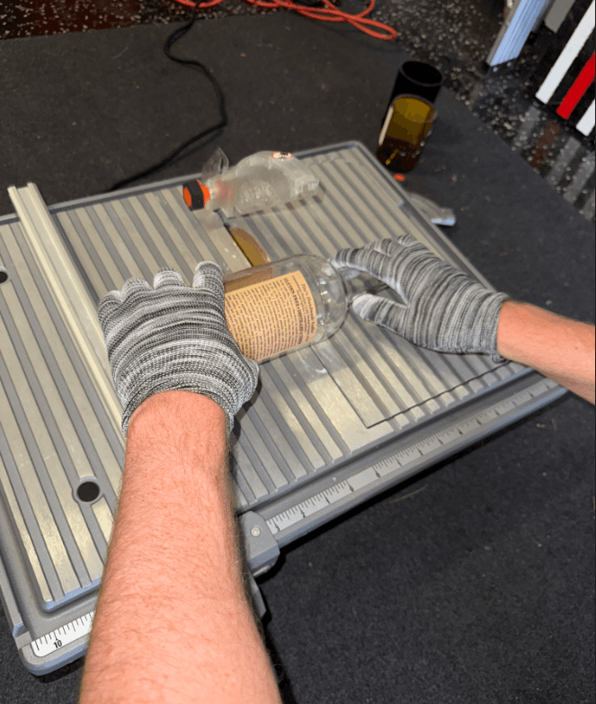 Bottle being precisely cut on a wet tile saw for candle making